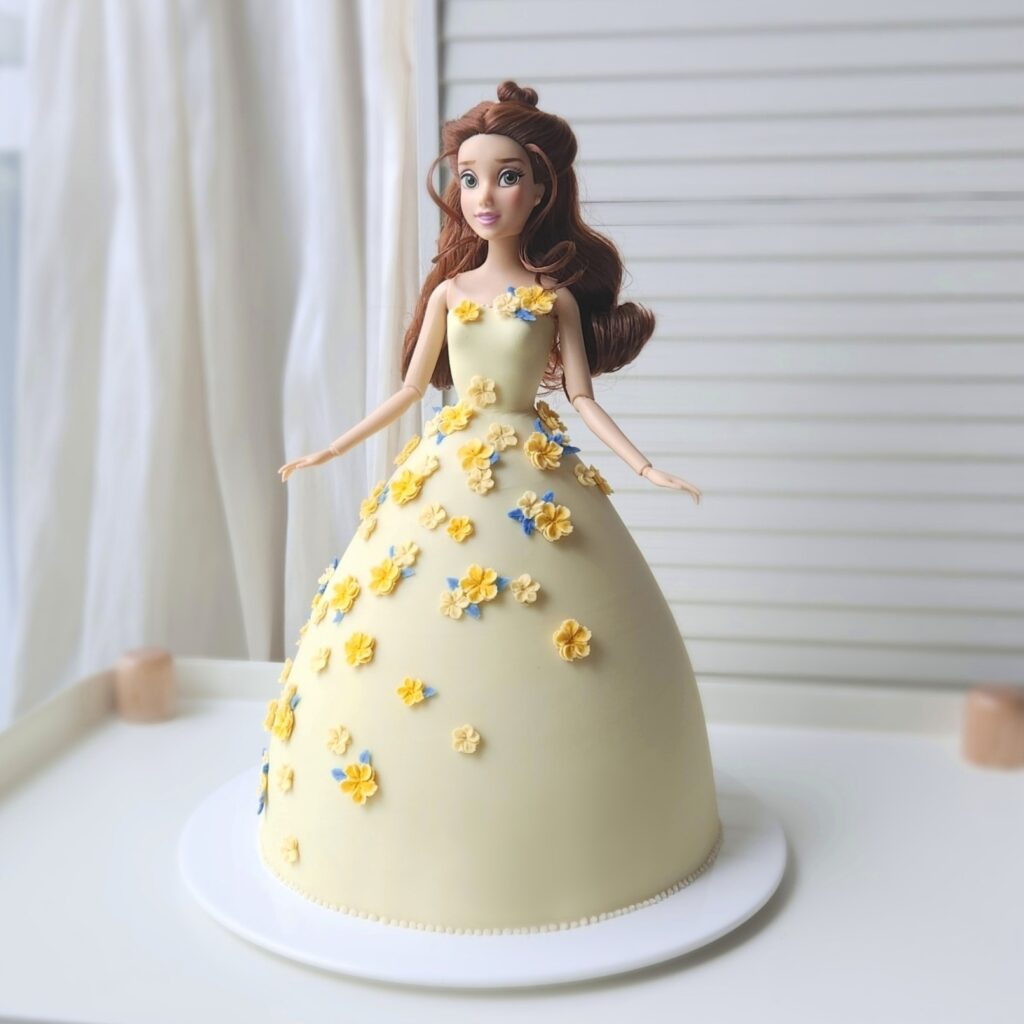 인형을 이용해 만든 드레스 모양의 케이크로, 폭신하고 부드러운 쌀 제누아즈를 버터크림으로 장식합니다.